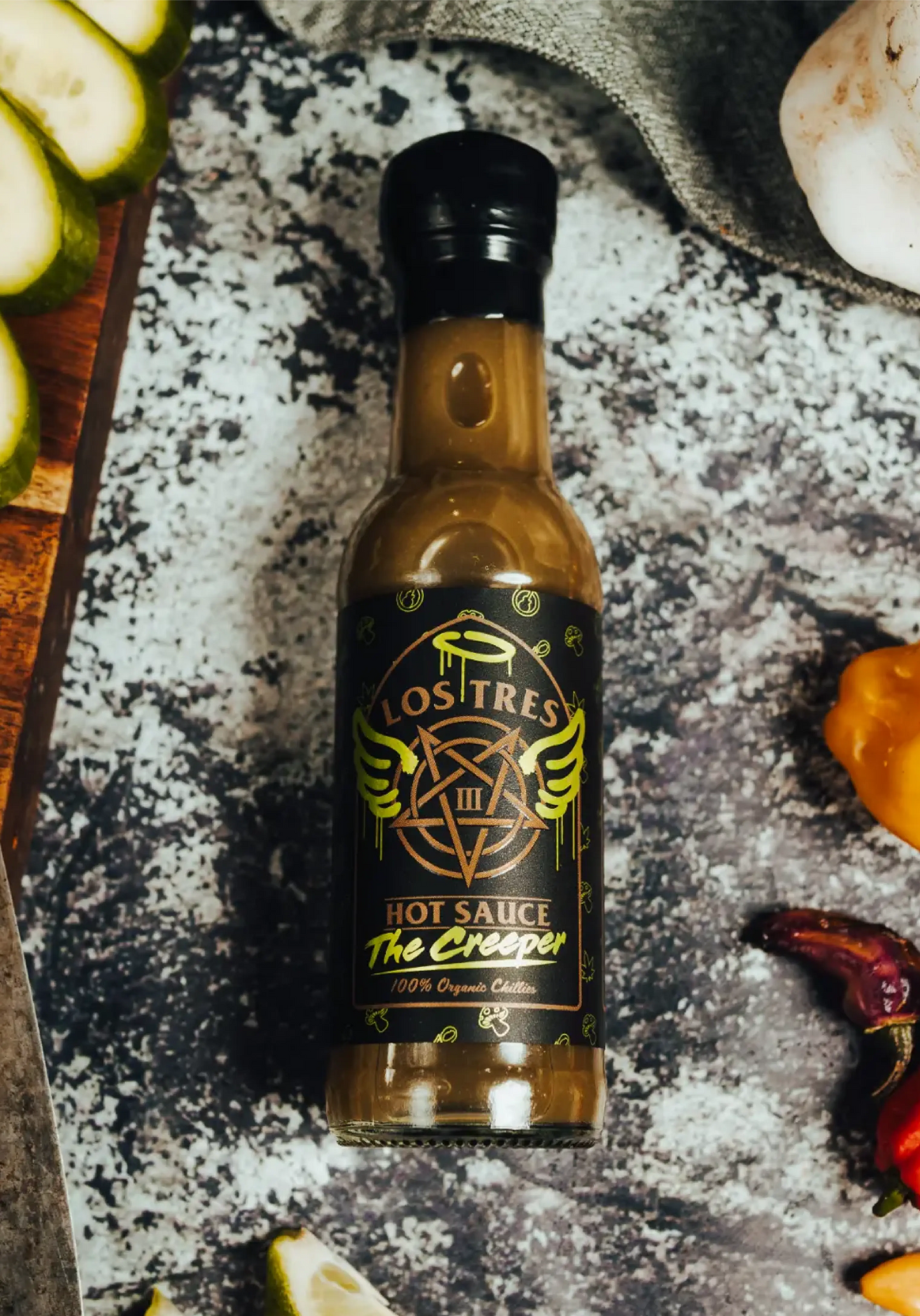 bottle of hot sauce with green, black and gold label. Has the name The Creeper